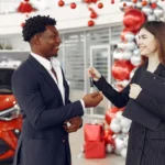Car dealer handing car keys to a happy customer in a showroom in Australia