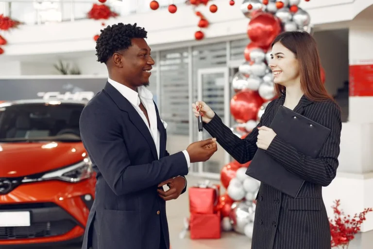 Car dealer handing car keys to a happy customer in a showroom in Australia